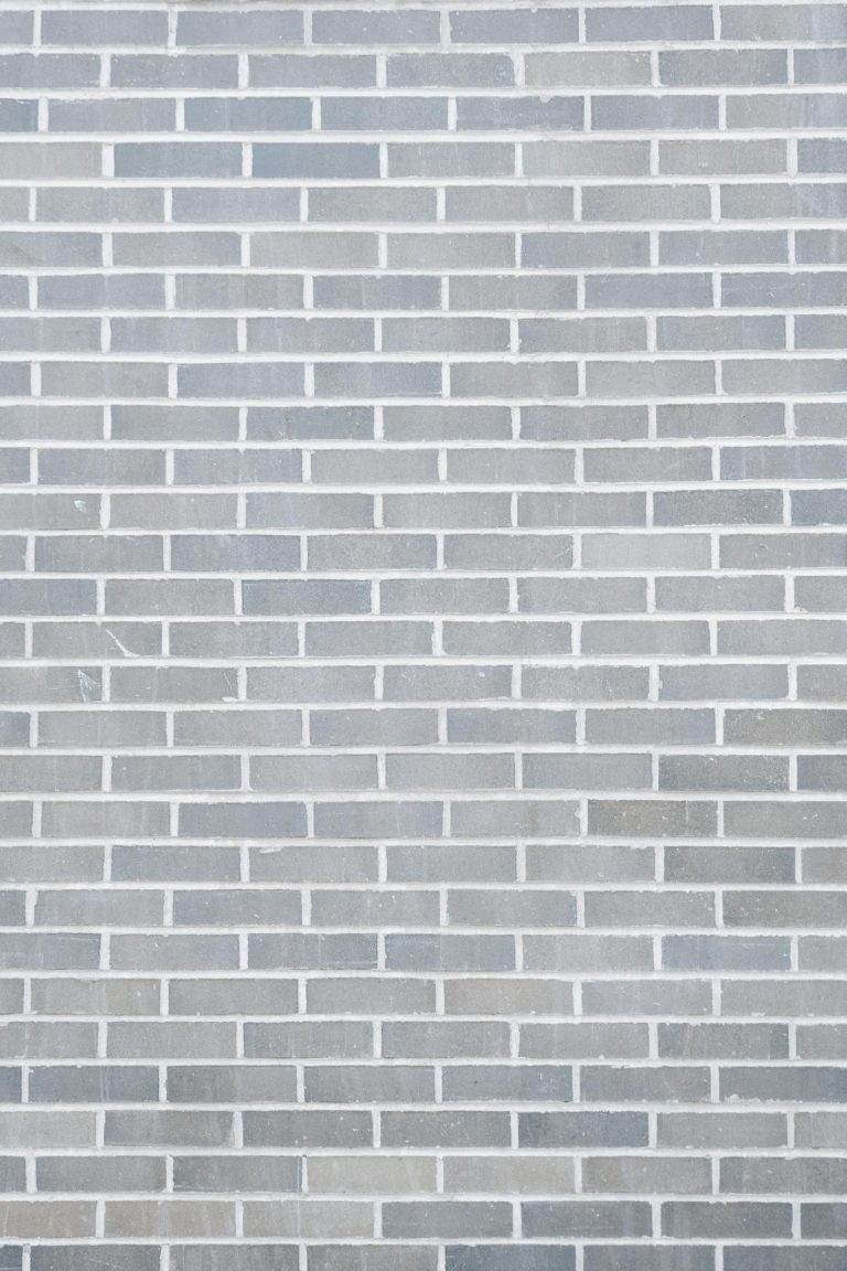 Full frame background of empty gray wall build with rows of brick blocks